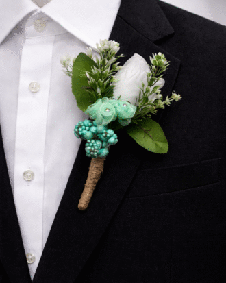 mint green tie with floral boutonniere on black suit groom wedding accessory set