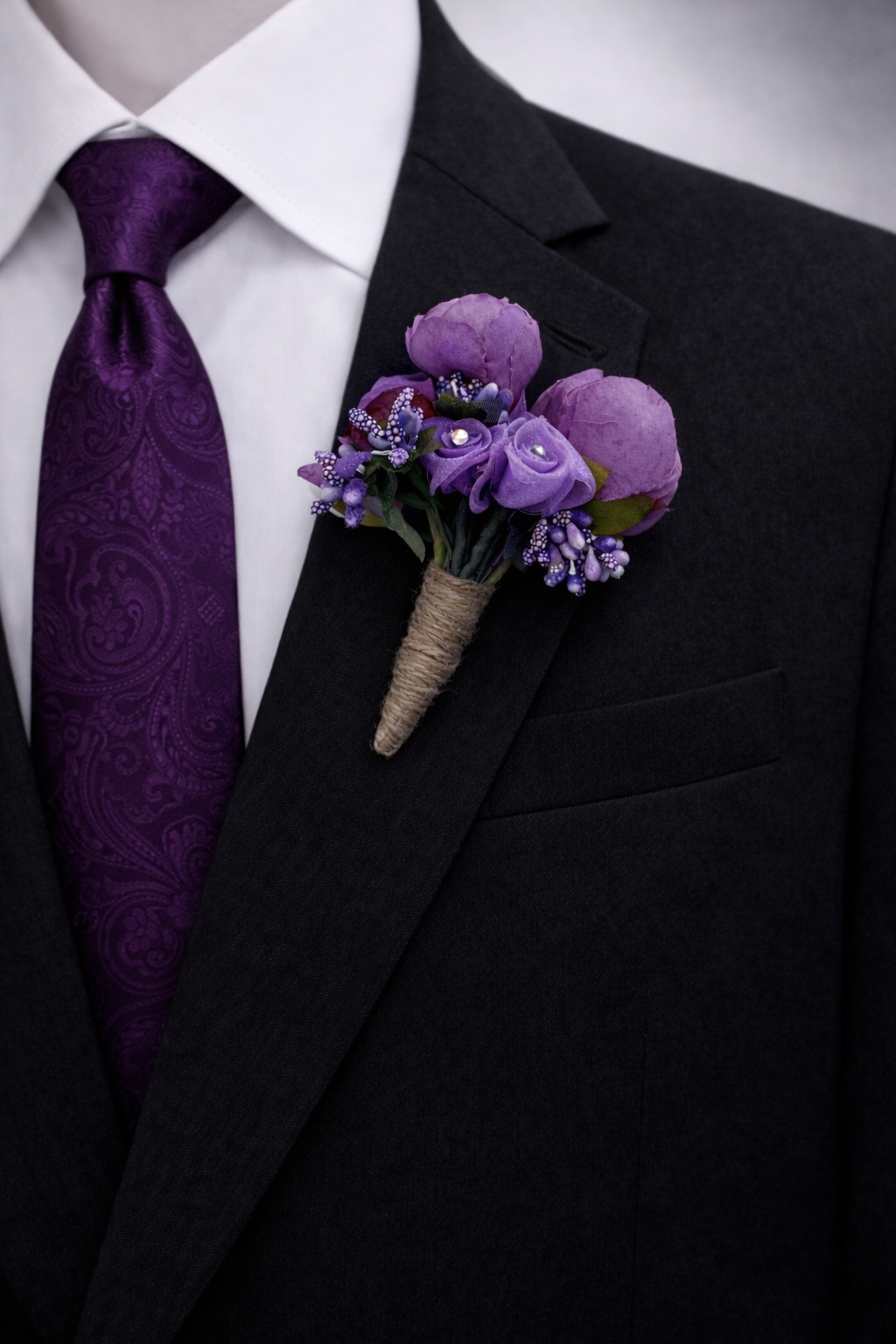 deep purple boutonniere with matching paisley tie on black suit groom wedding accessory set